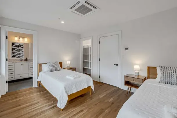 A modern, well-lit bedroom with twin beds and private access to a bathroom at a drug and alcohol detox center in Nashville, providing a serene recovery space.