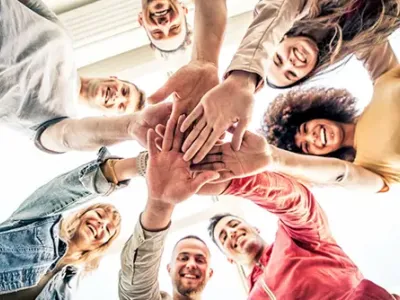 A circle of smiling individuals joining hands, symbolizing unity and hope in the recovery journey at drug and alcohol treatment centers in Tennessee.