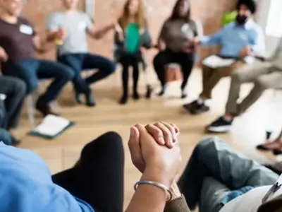 A group therapy session with participants holding hands, symbolizing unity and support offered at drug and alcohol treatment centers in Tennessee.