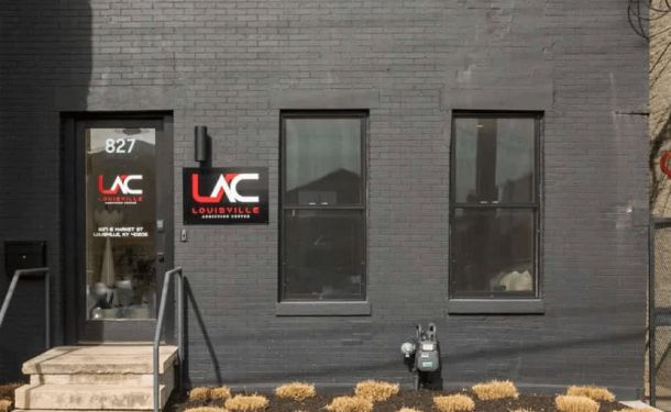 The entrance to a drug and alcohol rehab center in Louisville, KY, showcasing a modern black exterior with clear signage and a welcoming pathway.