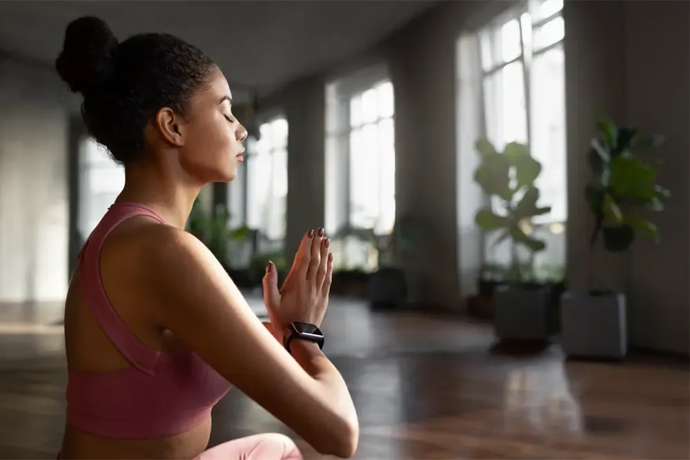 A woman practicing mindfulness meditation in a serene and spacious room, highlighting a holistic approach to healing at a drug and alcohol detox center in Nashville.