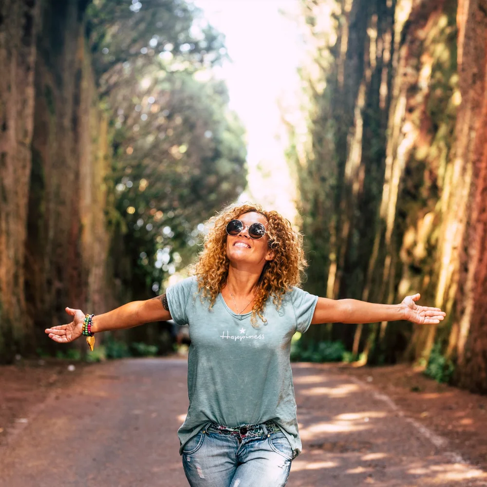  A joyful woman embracing life in a serene outdoor setting, symbolizing hope and recovery at a drug and alcohol detox center in Nashville.