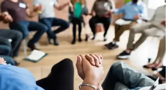 A support group session with individuals holding hands, fostering unity and healing at drug and alcohol treatment centers in Kentucky.